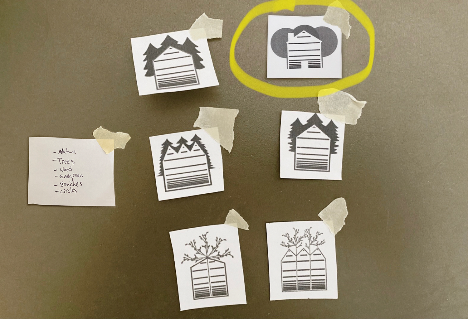 symphony woods logo sketches taped to a wall, exploring house and tree shapes